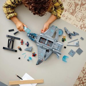 Child assembling a colorful LEGO spaceship, showcasing creativity in a cozy indoor setting.