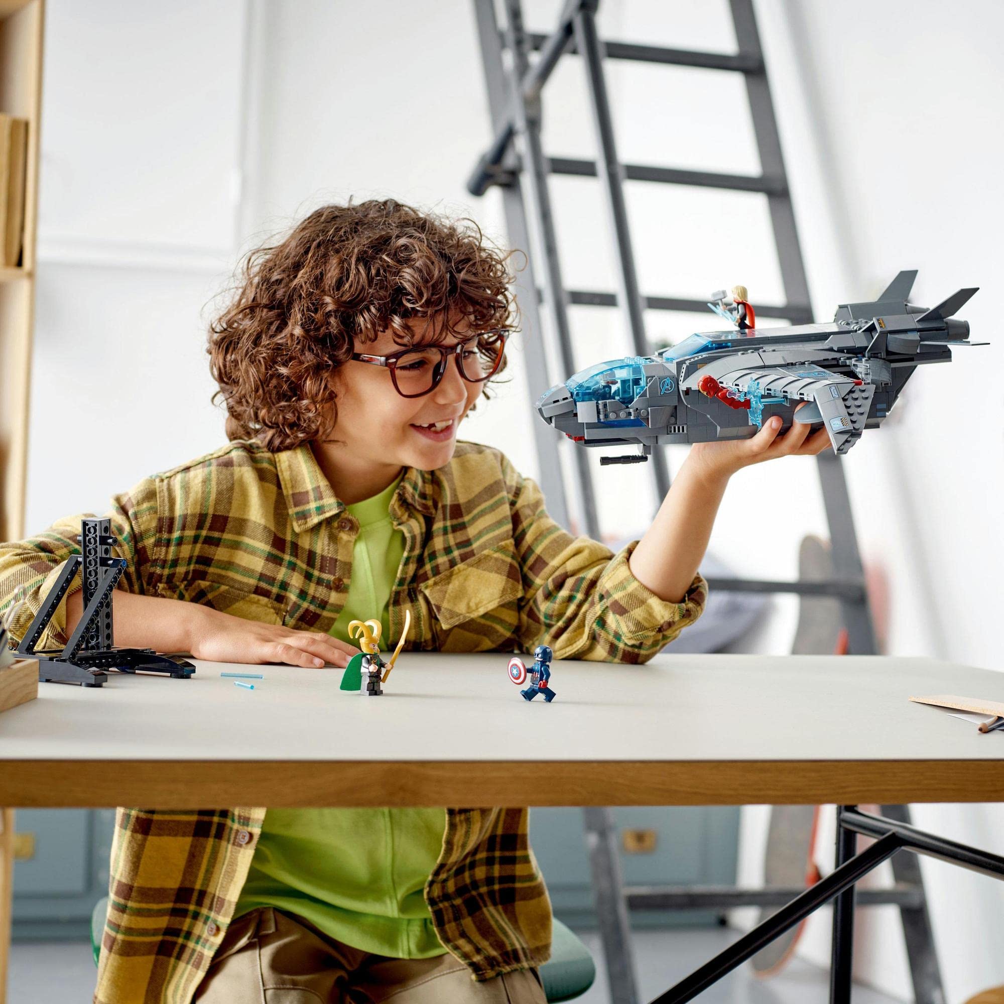Young boy with glasses joyfully builds a toy aircraft while immersed in imaginative play.