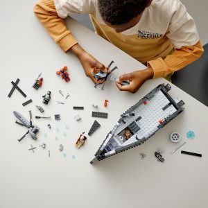 Child enthusiastically builds a colorful LEGO boat, surrounded by vibrant pieces and creativity.