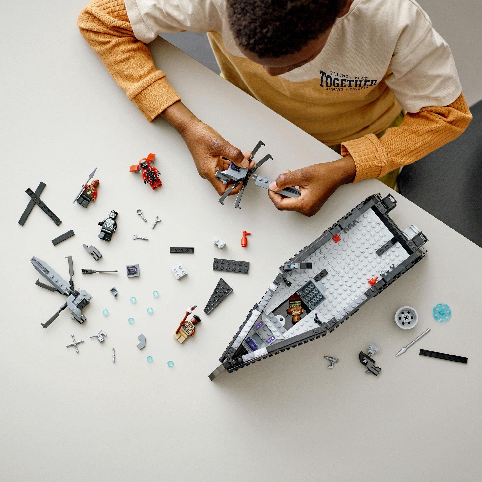 Child enthusiastically builds a colorful LEGO boat, surrounded by vibrant pieces and creativity.