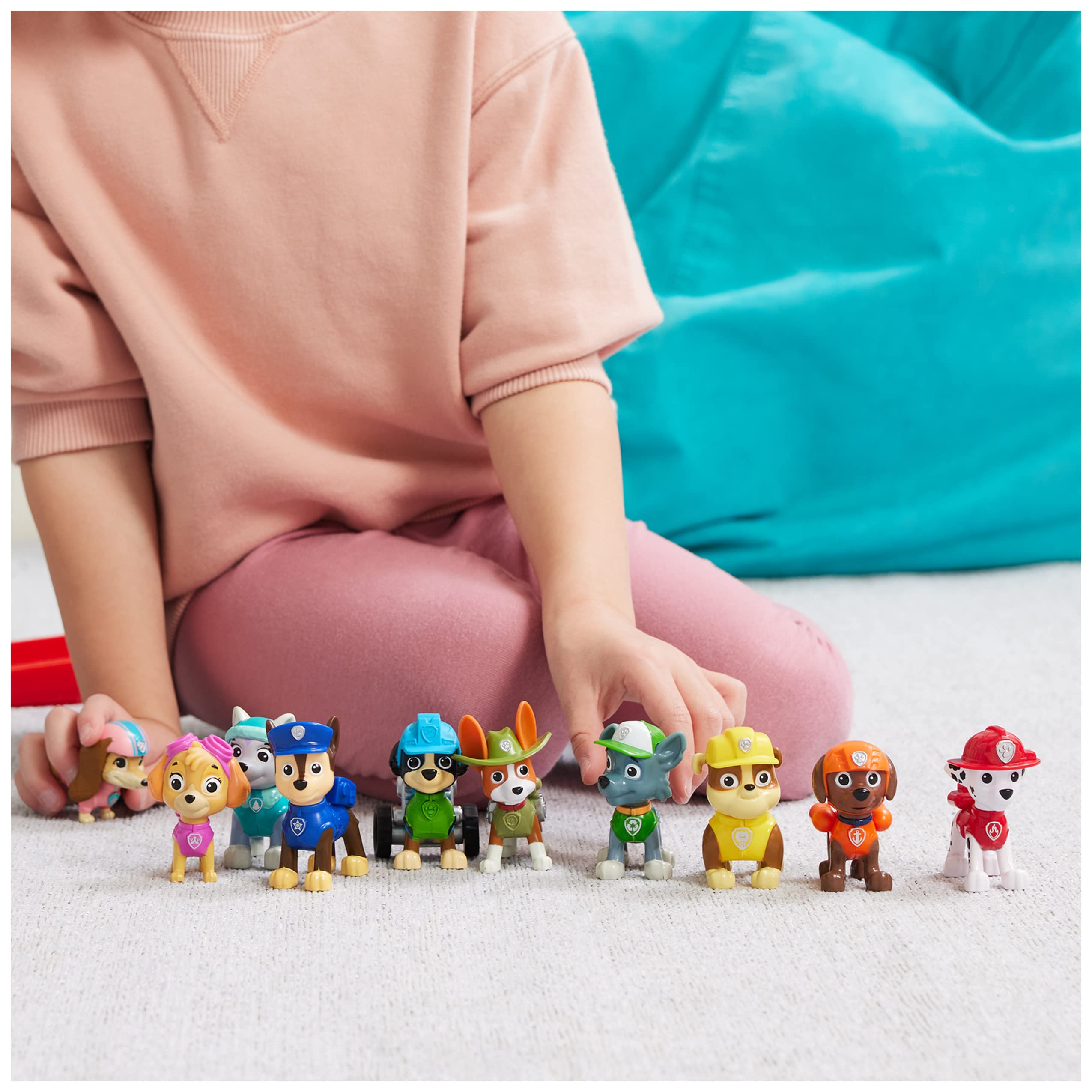 Childs hand engages with colorful toy figures, sparking imaginative play and storytelling.
