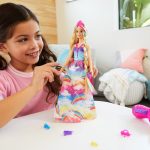 Joyful girl styles colorful doll in bright room, inspiring creativity and imagination during playtime.