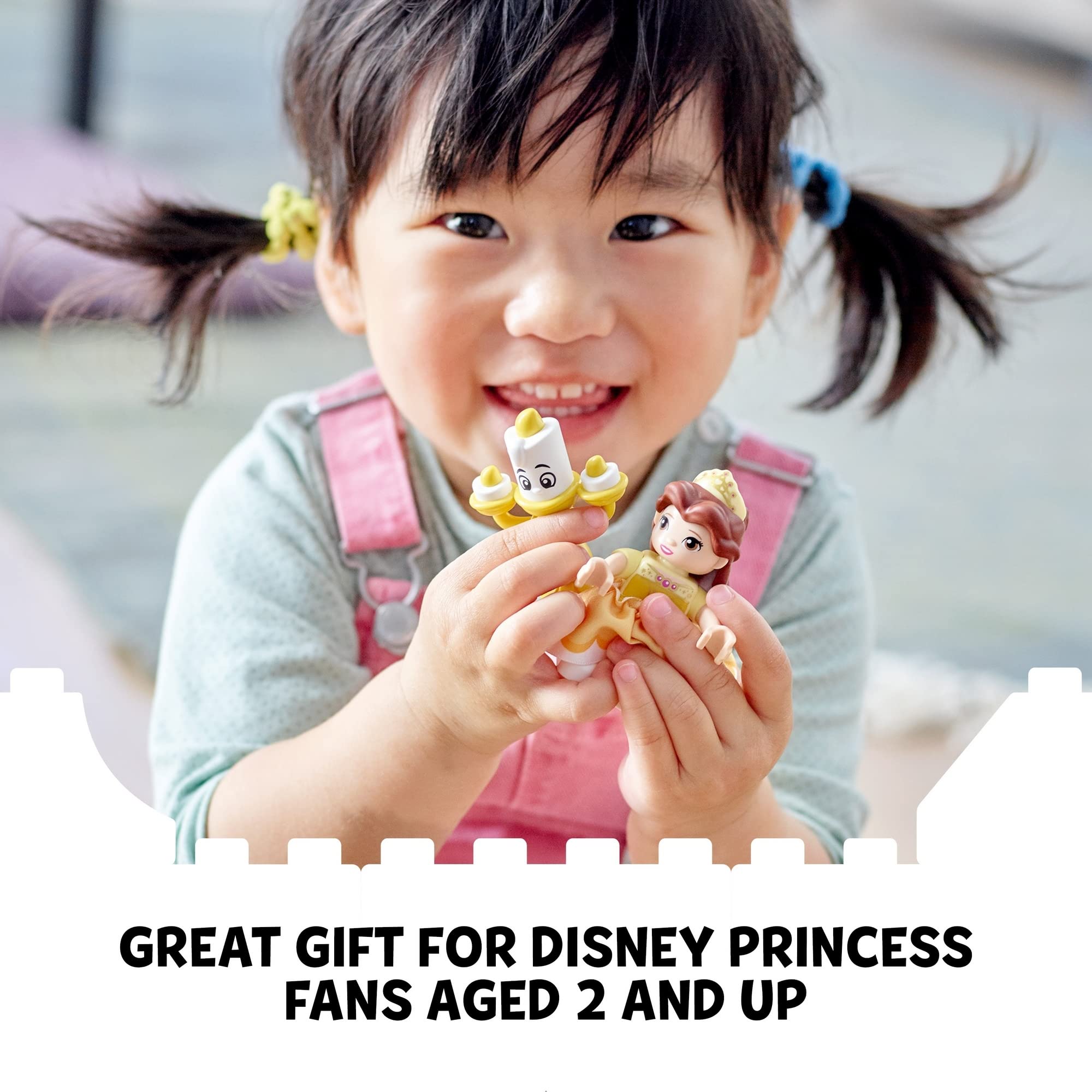 Happy girl playing with colorful Disney princess figurines in a cozy indoor setting.