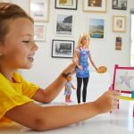 Joyful girl with dolls engaged in colorful art playtime in a cheerful, modern setting.