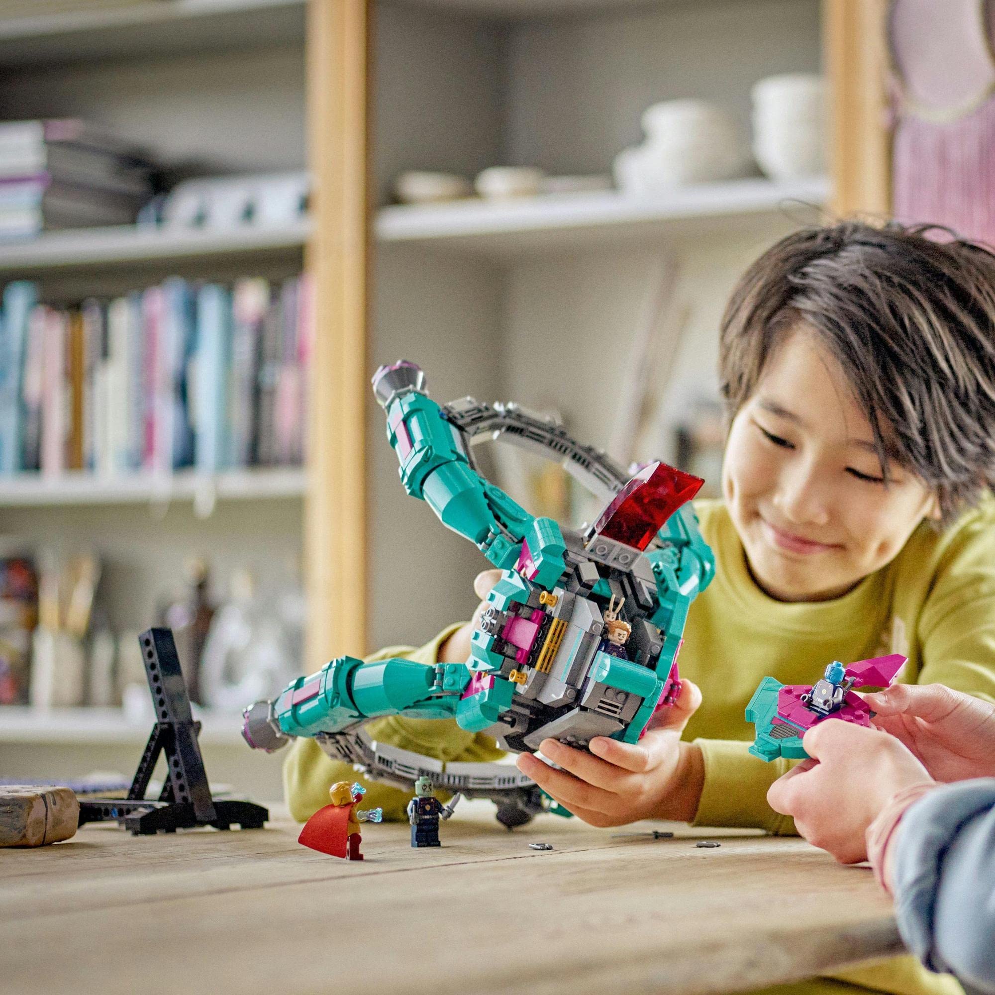 Child joyfully constructs a colorful LEGO structure with an adults supportive guidance in a cozy living room.
