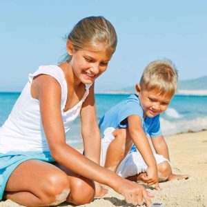 Joyful beach day: children play in sand, building creations and sharing laughter by the ocean.