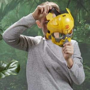 Boy excitedly plays with Bumblebee mask in a lush, adventurous green setting.