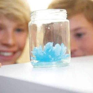 Boys fascinated by a vibrant blue science experiment in a jar, enjoying discovery together.