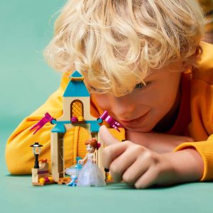 Child joyfully builds a colorful LEGO fairy tale scene with whimsical decorations and a princess figure.