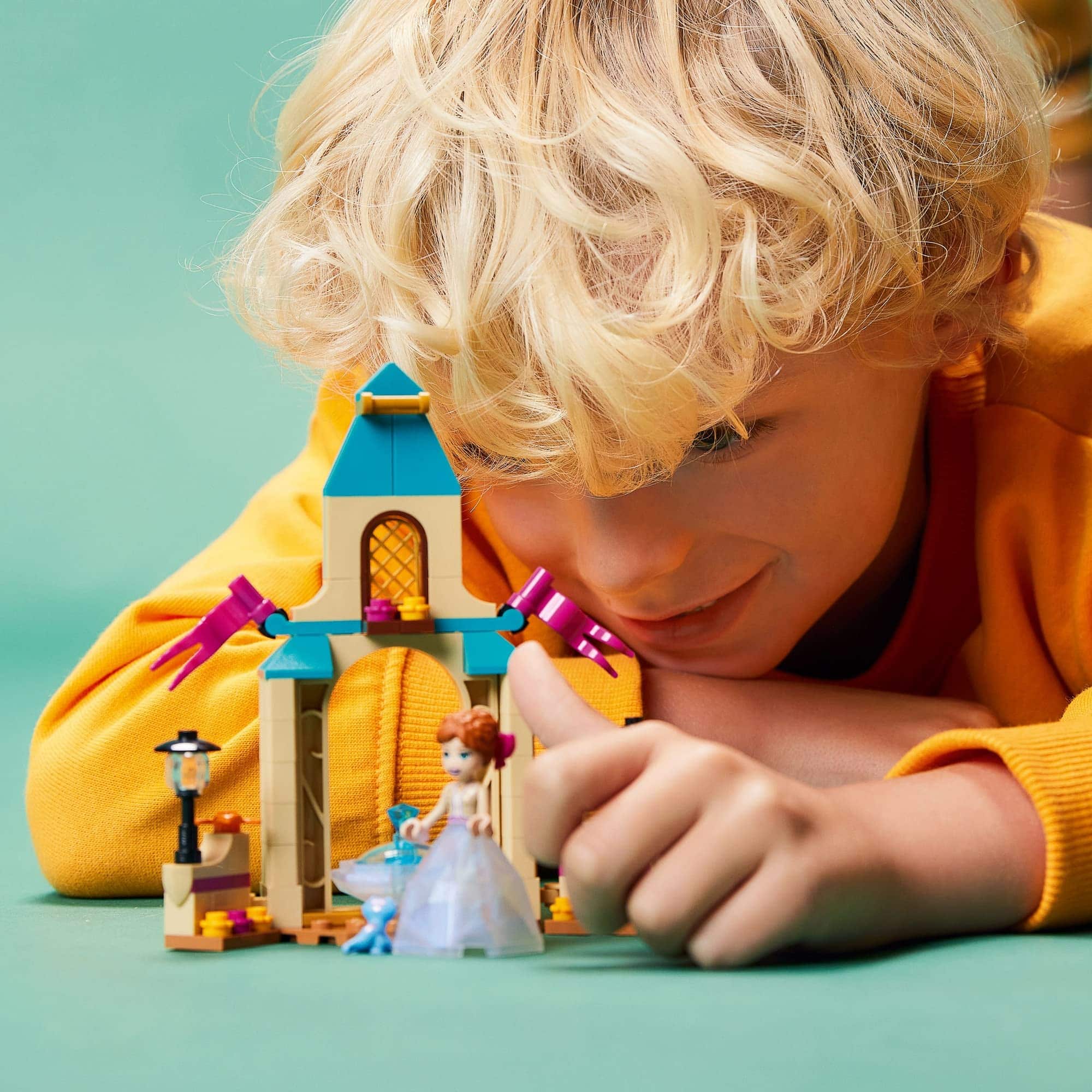 Child joyfully builds a colorful LEGO fairy tale scene with whimsical decorations and a princess figure.