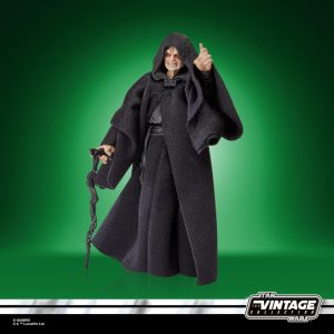 Mysterious action figure in black cloak with gnarled staff, set against a vibrant green backdrop.