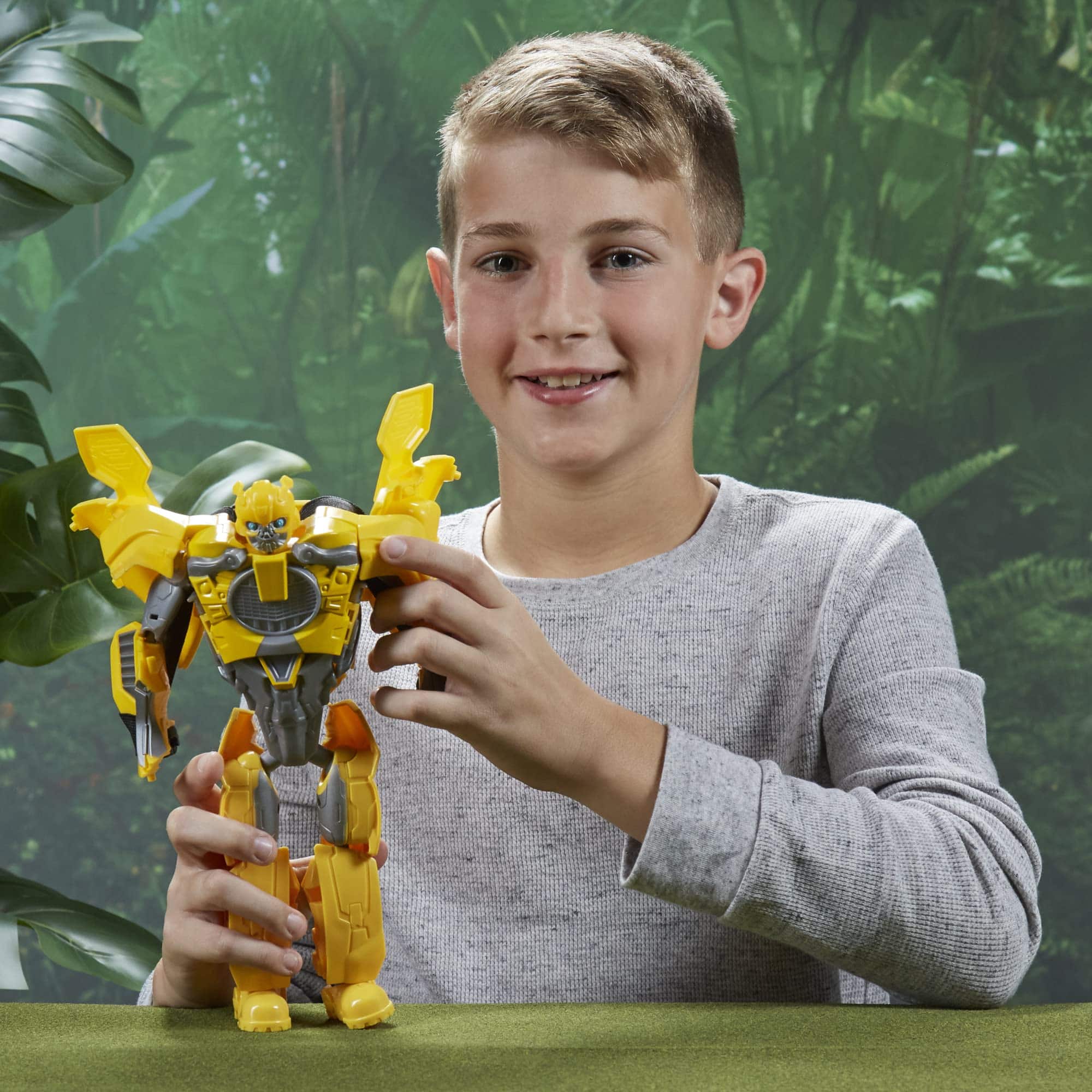 Boy joyfully playing with colorful robot toy in a lush tropical setting.