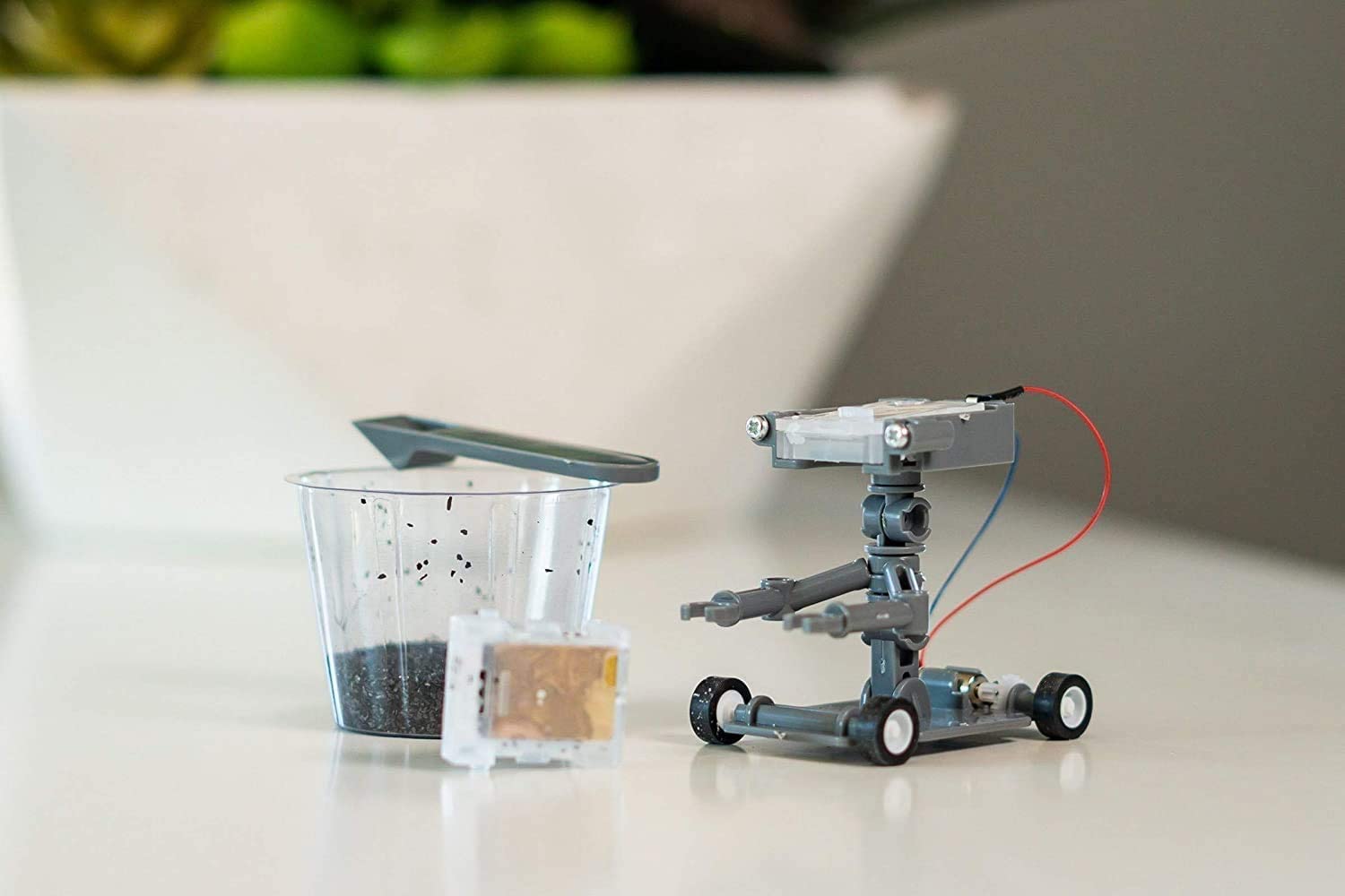 Intricate robotic gardening assistant next to soil cup, blending technology with nature in a workspace.