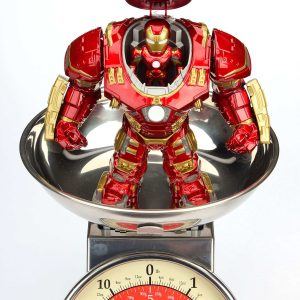 Superhero action figure in vibrant armor balances playfully on a classic kitchen scale.