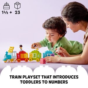 Toddler explores a colorful train playset, learning numbers with engaging play and adult support.