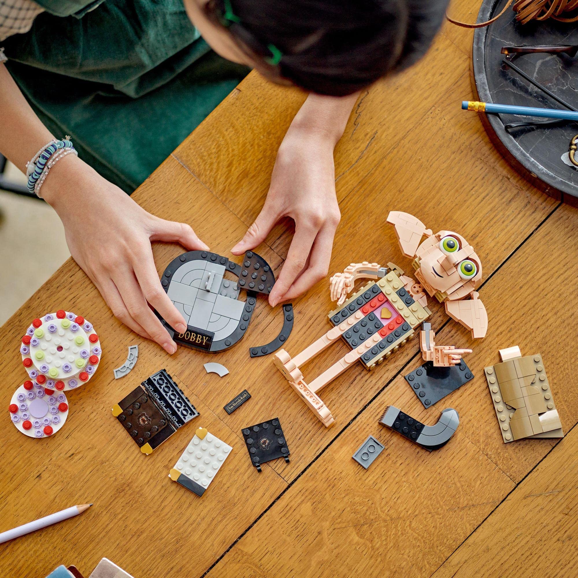 Young builder creating a colorful LEGO fantasy character on a sunny craft table.