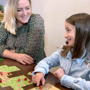 Joyful board game fun between a woman and a girl in a cozy setting.