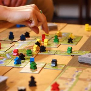 Engaging board game session with colorful meeples on an illustrated wooden table.