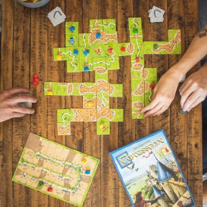 Engaging Carcassonne gameplay with vibrant tiles and friendly competition on a rustic table.
