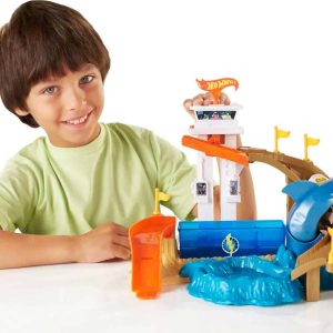 Joyful boy plays with colorful ocean adventure toy set featuring shark and vibrant structures.
