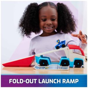 Joyful girl with curly hair excitedly plays with colorful truck and launch ramp toy.