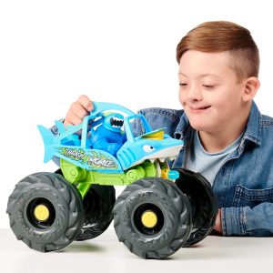 Excited boy playing with a colorful shark monster truck toy in imaginative playtime.