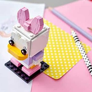 Colorful LEGO cartoon character with bunny ears in a creative workspace of drawings and supplies.