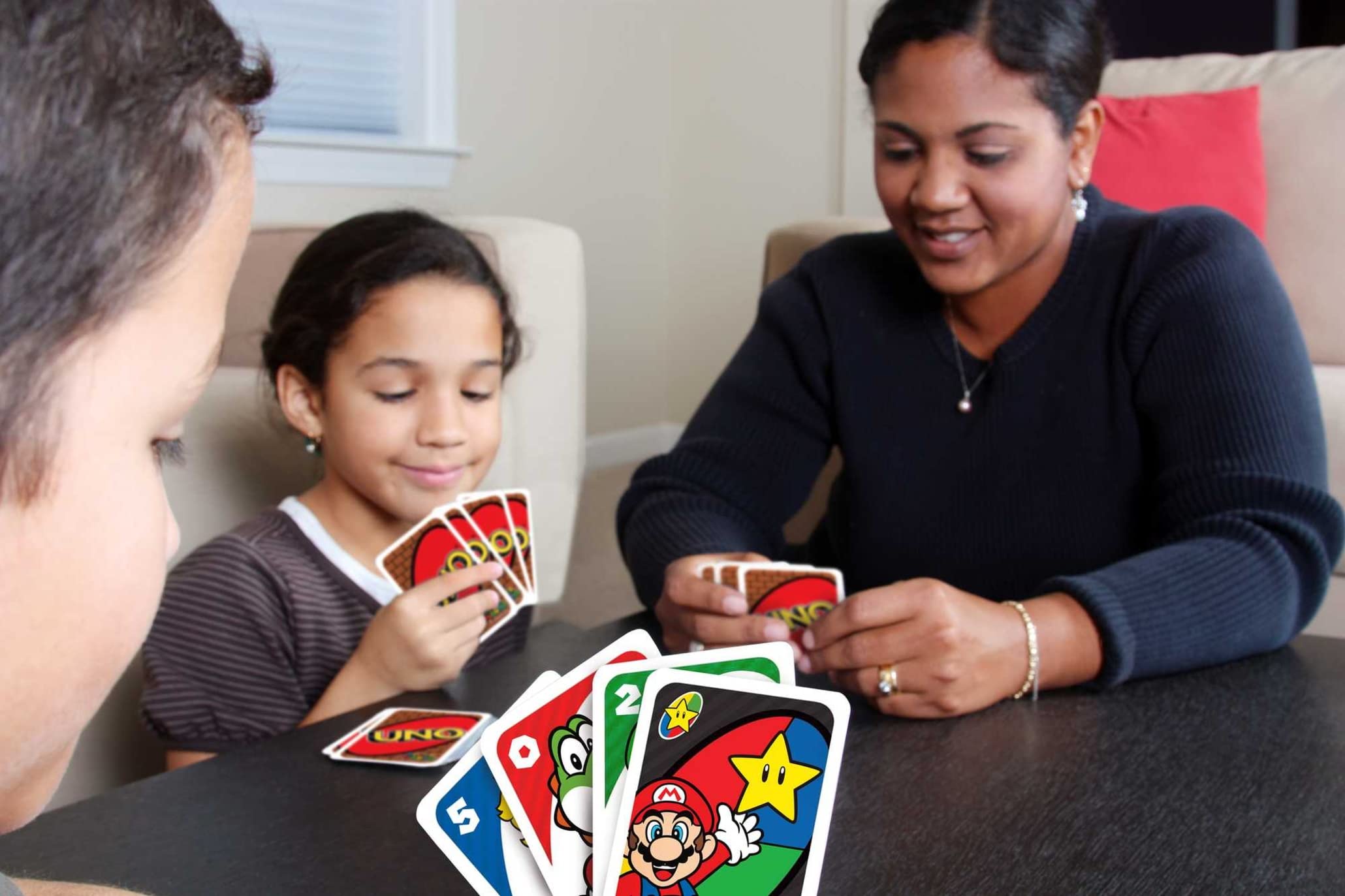 Family bonding over a colorful card game in a cozy indoor setting.