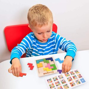 Child intently solving a colorful wooden puzzle at a white table, enhancing cognitive skills.