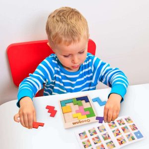 Young boy solving a colorful wooden puzzle, demonstrating focus and problem-solving skills.