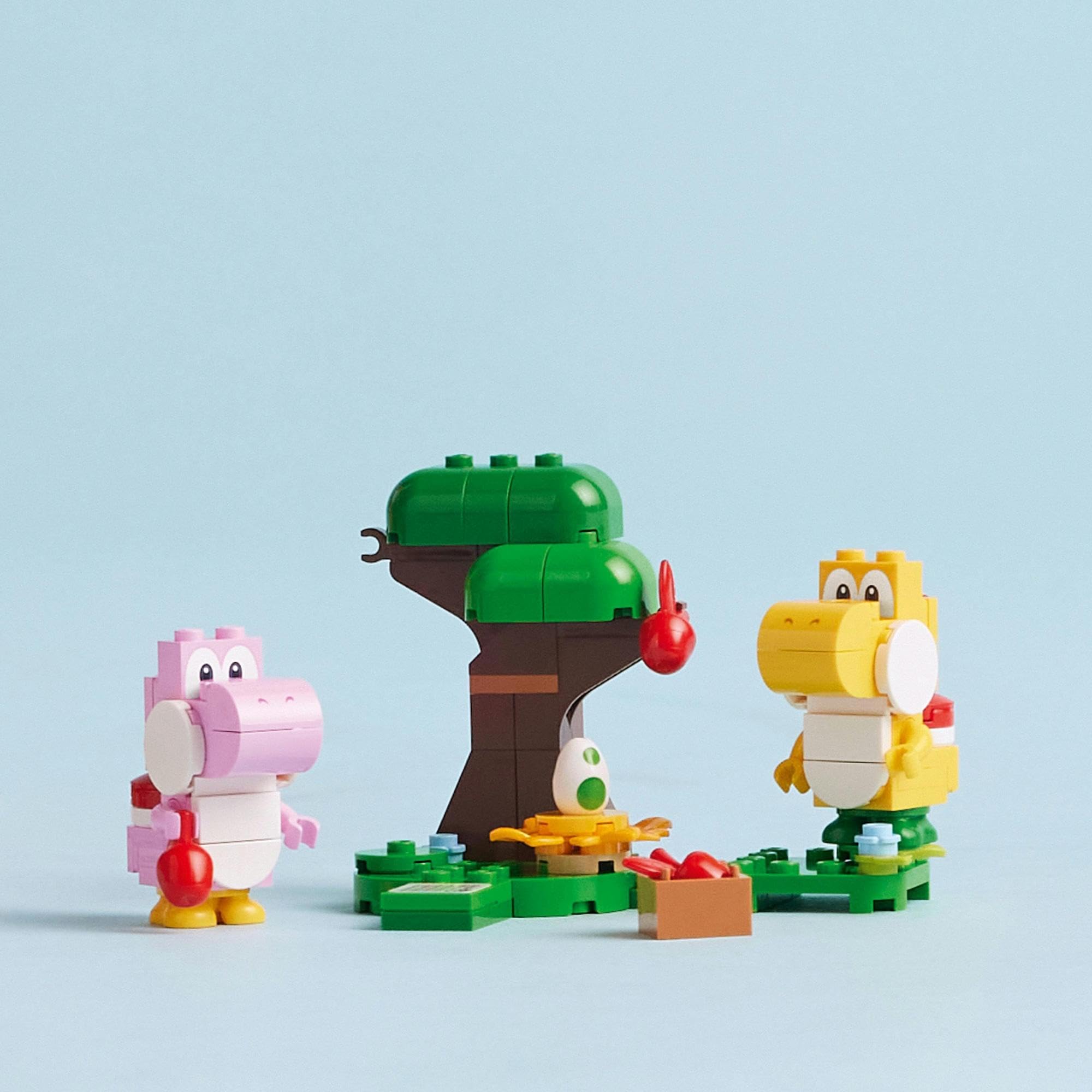 Colorful dinosaur characters playfully interact in a vibrant block building scene with a lush tree.