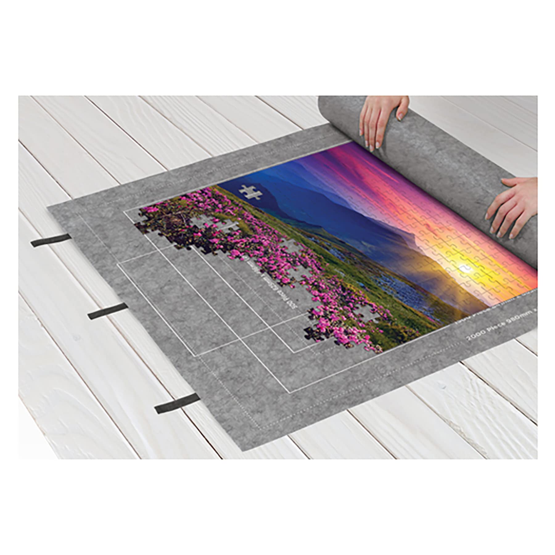 Person unrolls a vibrant sunset landscape poster showcasing rolling hills and blooming azaleas.