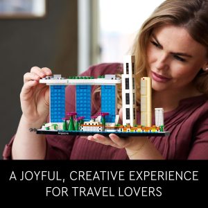 Cheerful woman explores colorful LEGO city model, celebrating travel and creativity in a modern space.