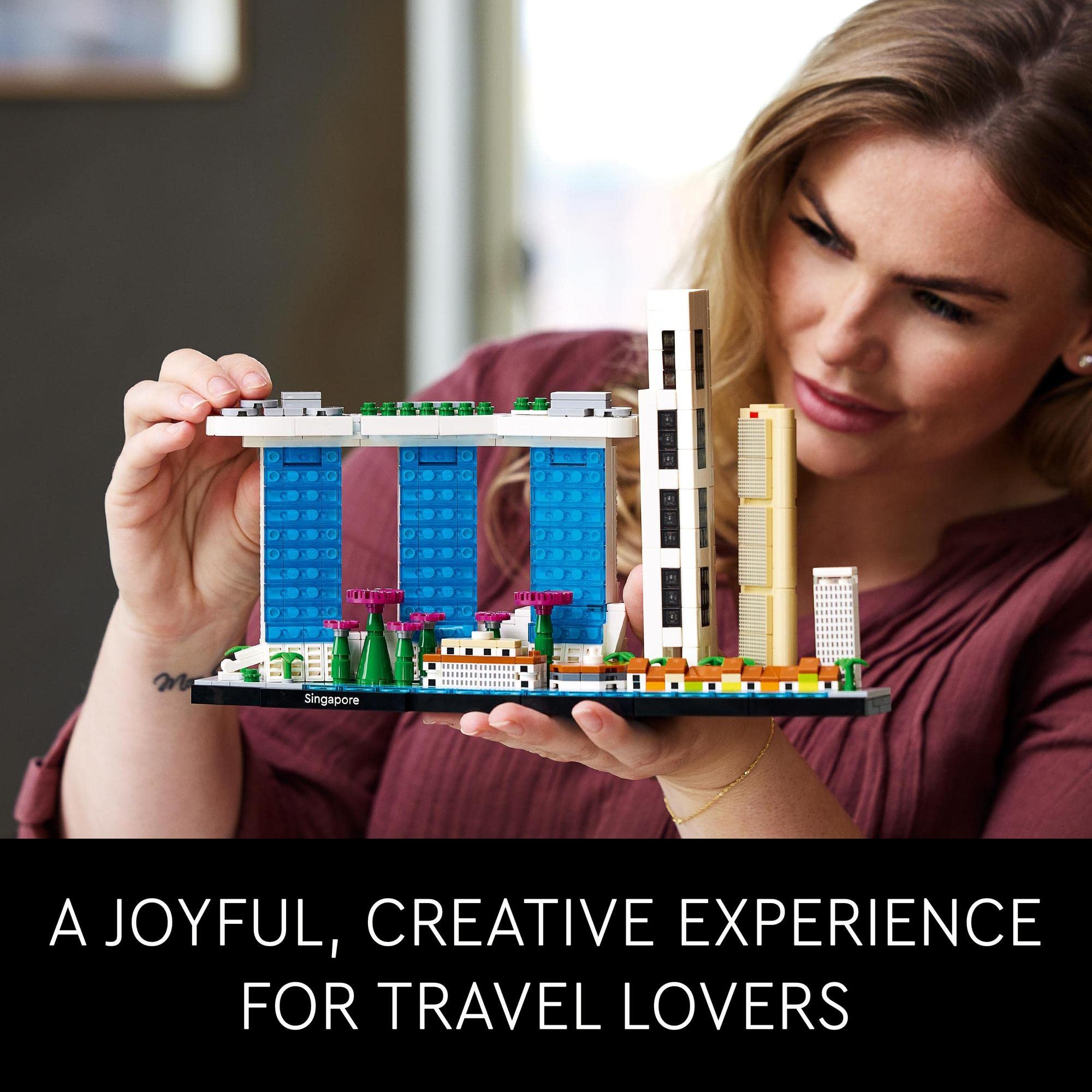 Cheerful woman explores colorful LEGO city model, celebrating travel and creativity in a modern space.