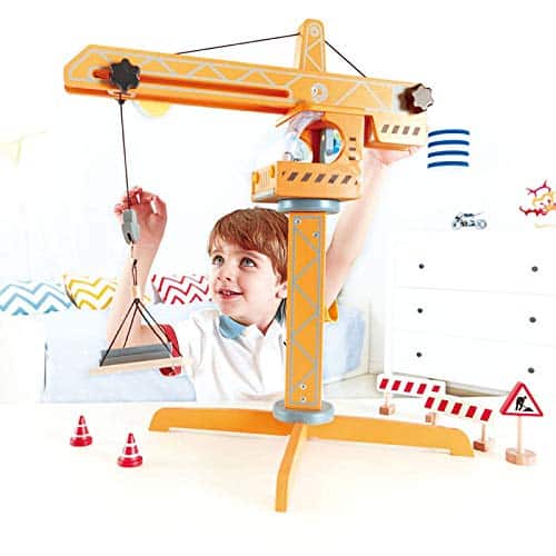 Joyful boy plays with yellow construction crane toy, enhancing creativity and motor skills in vibrant setting.