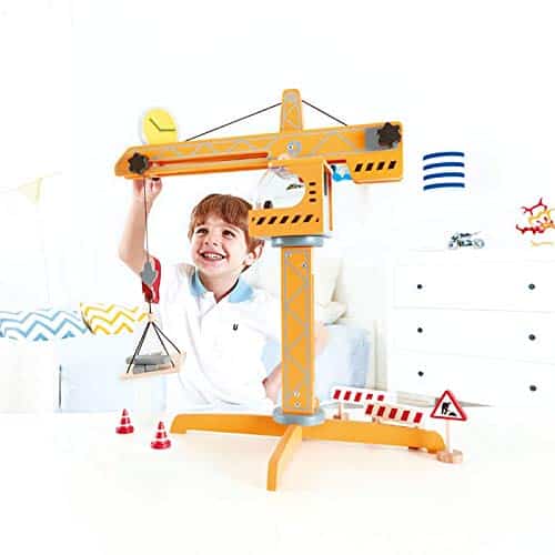Child joyfully plays with a bright yellow toy crane in a colorful, fun-filled setting.