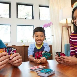 Family members enjoy a lively card game, sharing laughter and joy in a sunlit room.