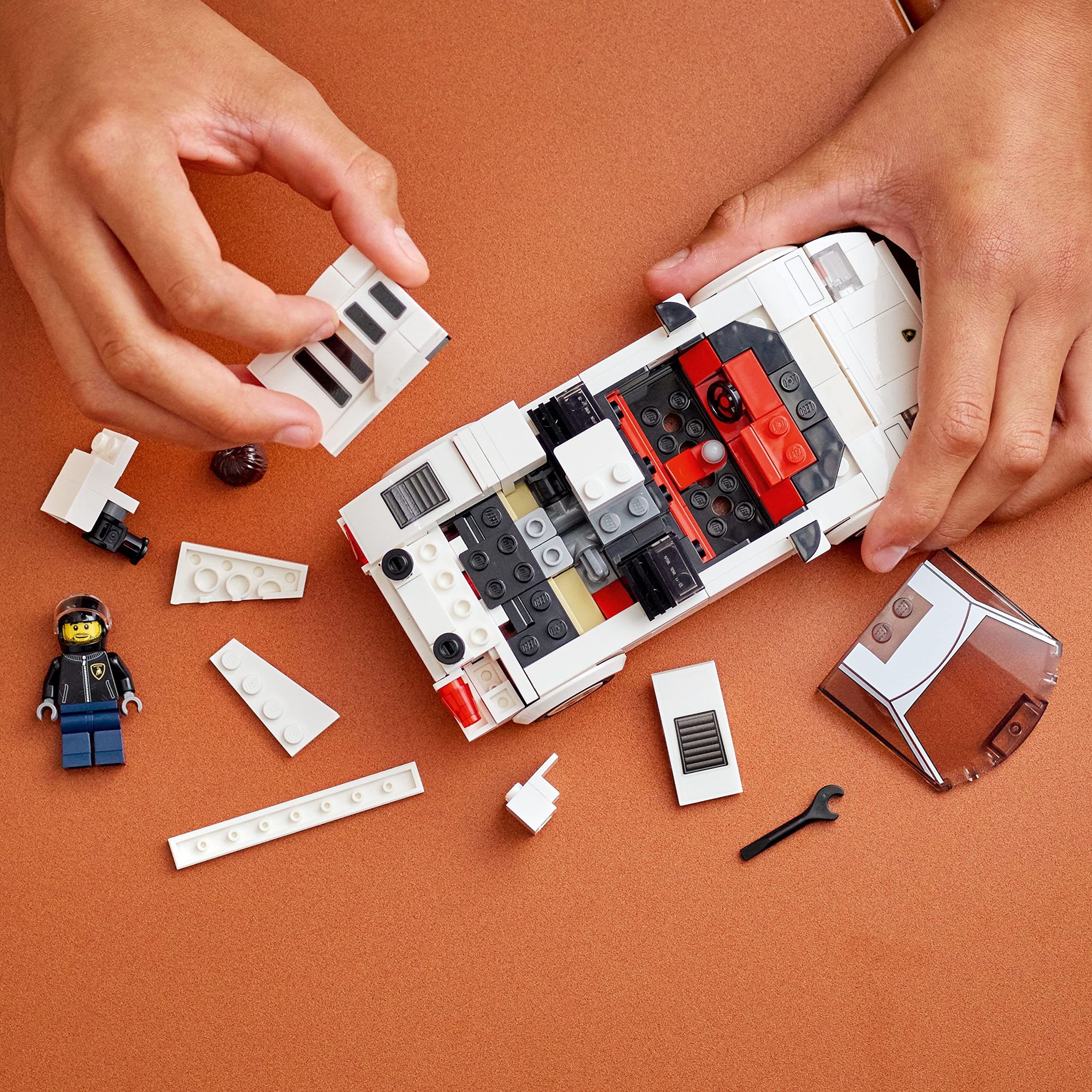 Hands building a colorful LEGO vehicle, showcasing creativity with vibrant blocks and a miniature figure.