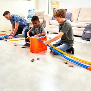 Family assembling colorful race track in a bright living room, showcasing teamwork and creativity.