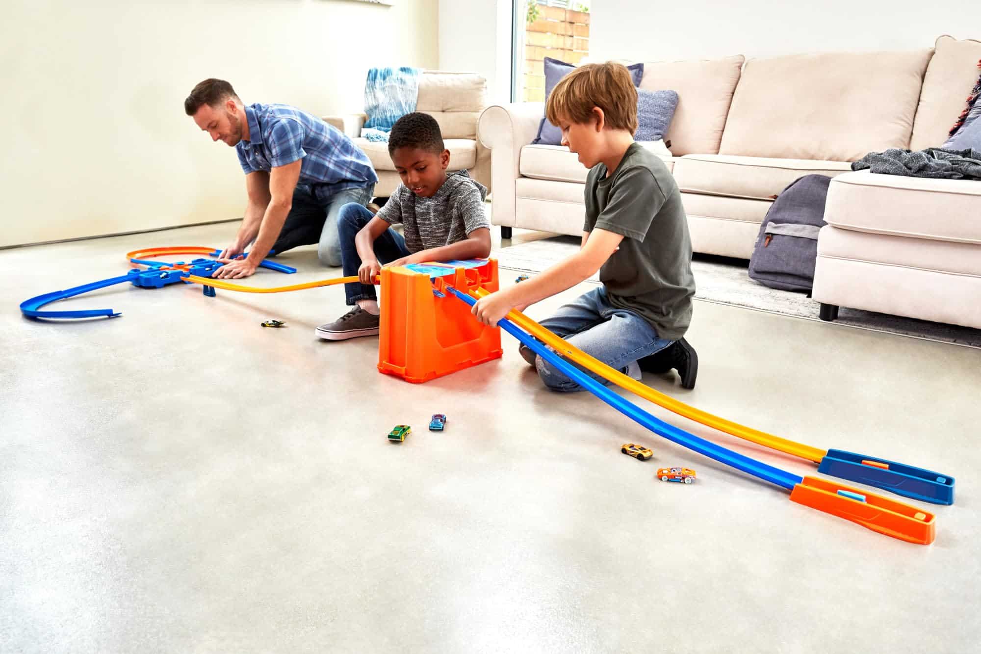 Family assembling colorful race track in a bright living room, showcasing teamwork and creativity.
