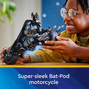 Joyful child in yellow shirt plays with detailed Bat-Pod motorcycle toy from Batman franchise.