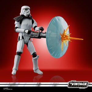 Stormtrooper action figure with blaster and blue energy shield against a bold red backdrop.