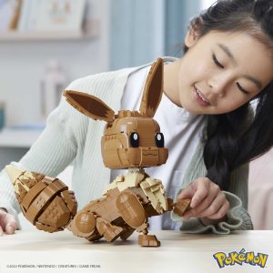 Young girl joyfully constructs a LEGO model of Eevee in a cozy, creative setting.
