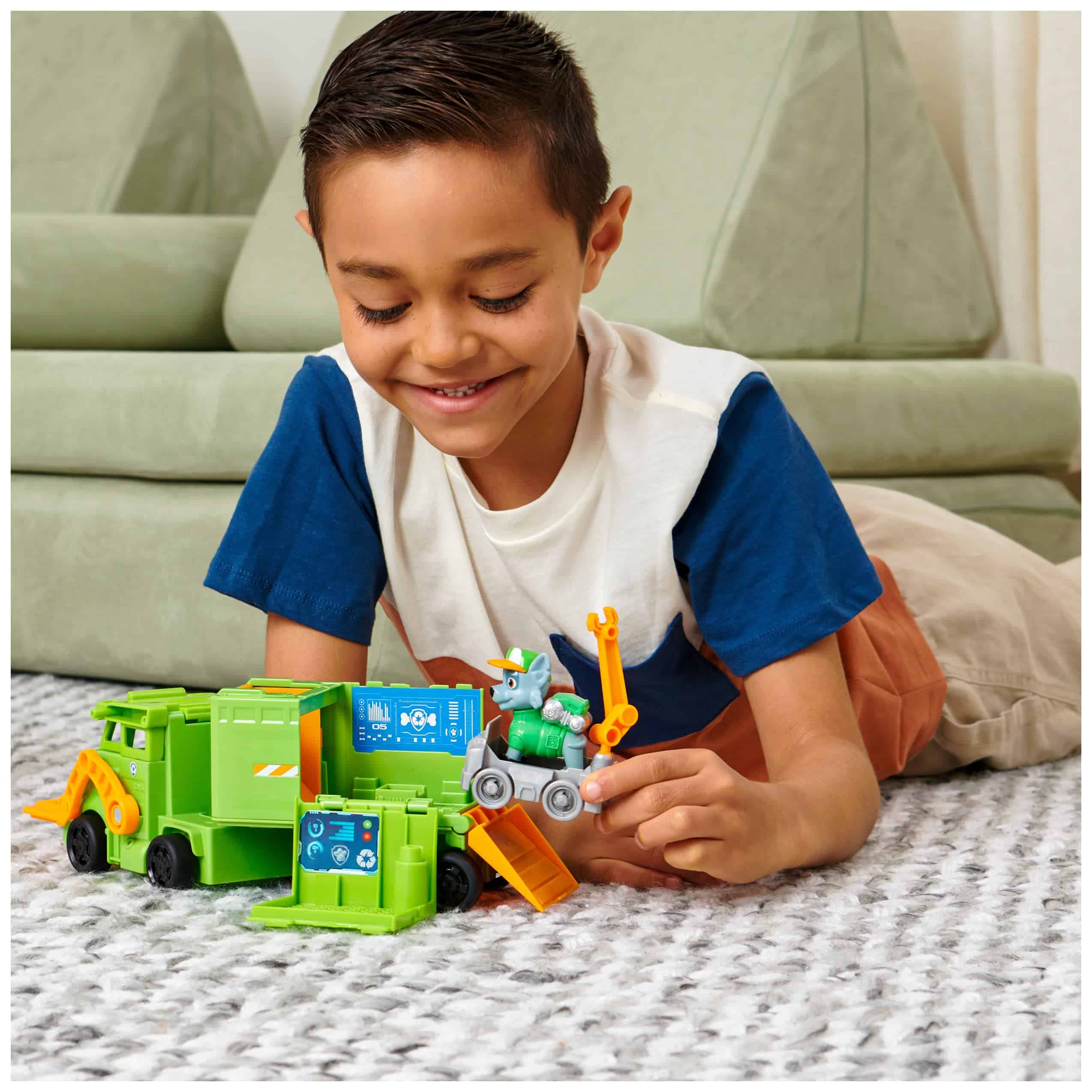 Young boy happily engages with a colorful garbage truck set, inspiring creativity and imaginative play.