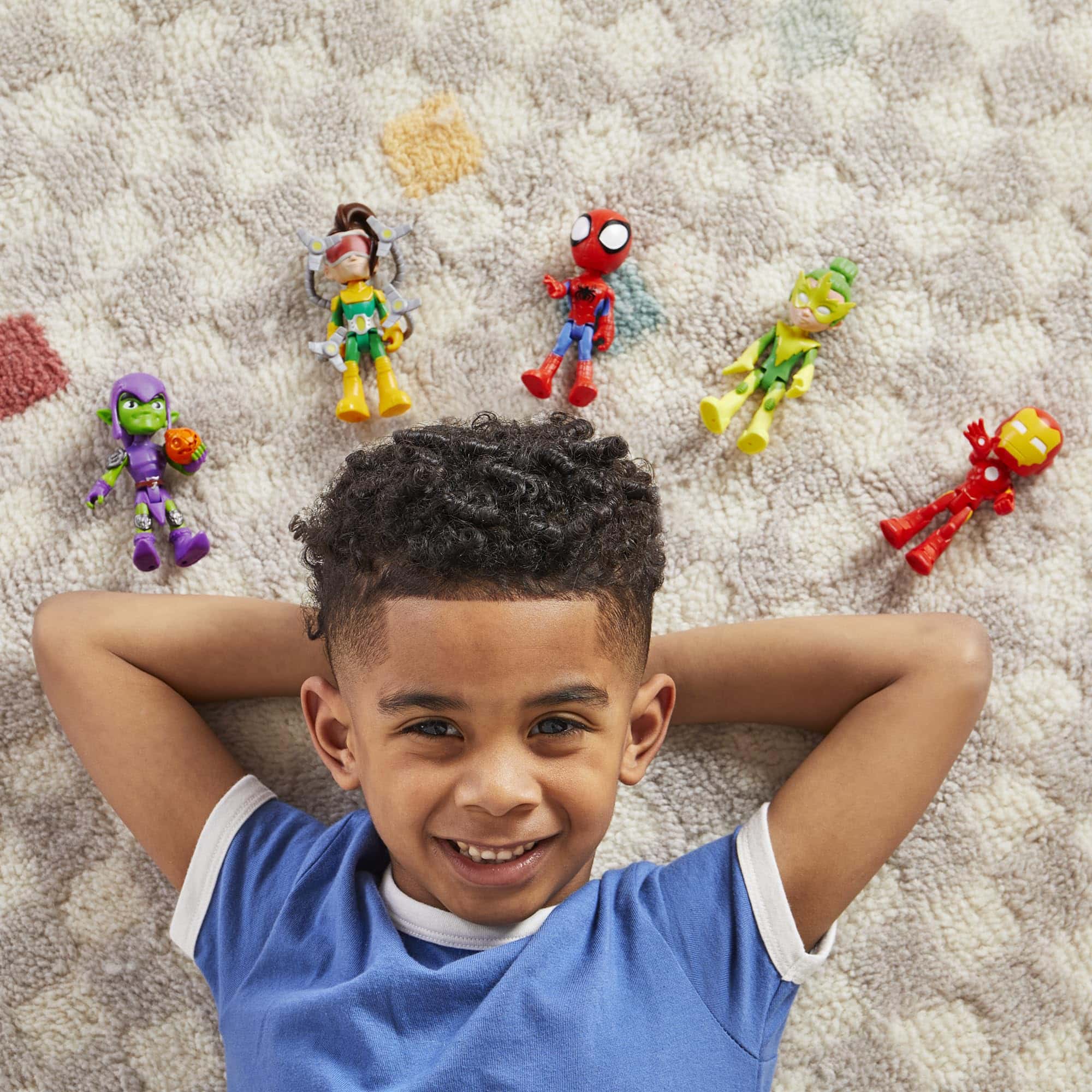 Joyful boy playing with superhero action figures on cozy carpet, embracing childhood imagination and adventure.