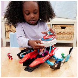 Child with curly hair enjoys imaginative play with colorful vehicle toy in bright playroom.