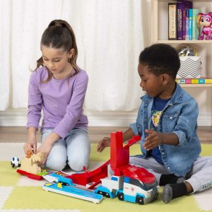Two children joyfully play with a colorful toy set in a sunny indoor playroom.