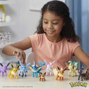 Young girl joyfully plays with colorful Eevee evolution figures, sparking creativity and imagination.