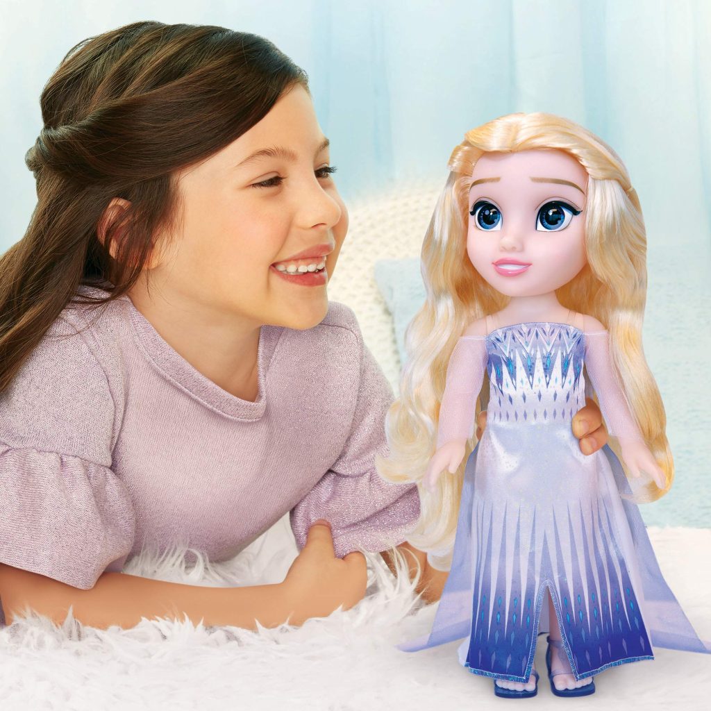 Young girl joyfully embraces a princess doll, celebrating imaginative play against a soft blue backdrop.