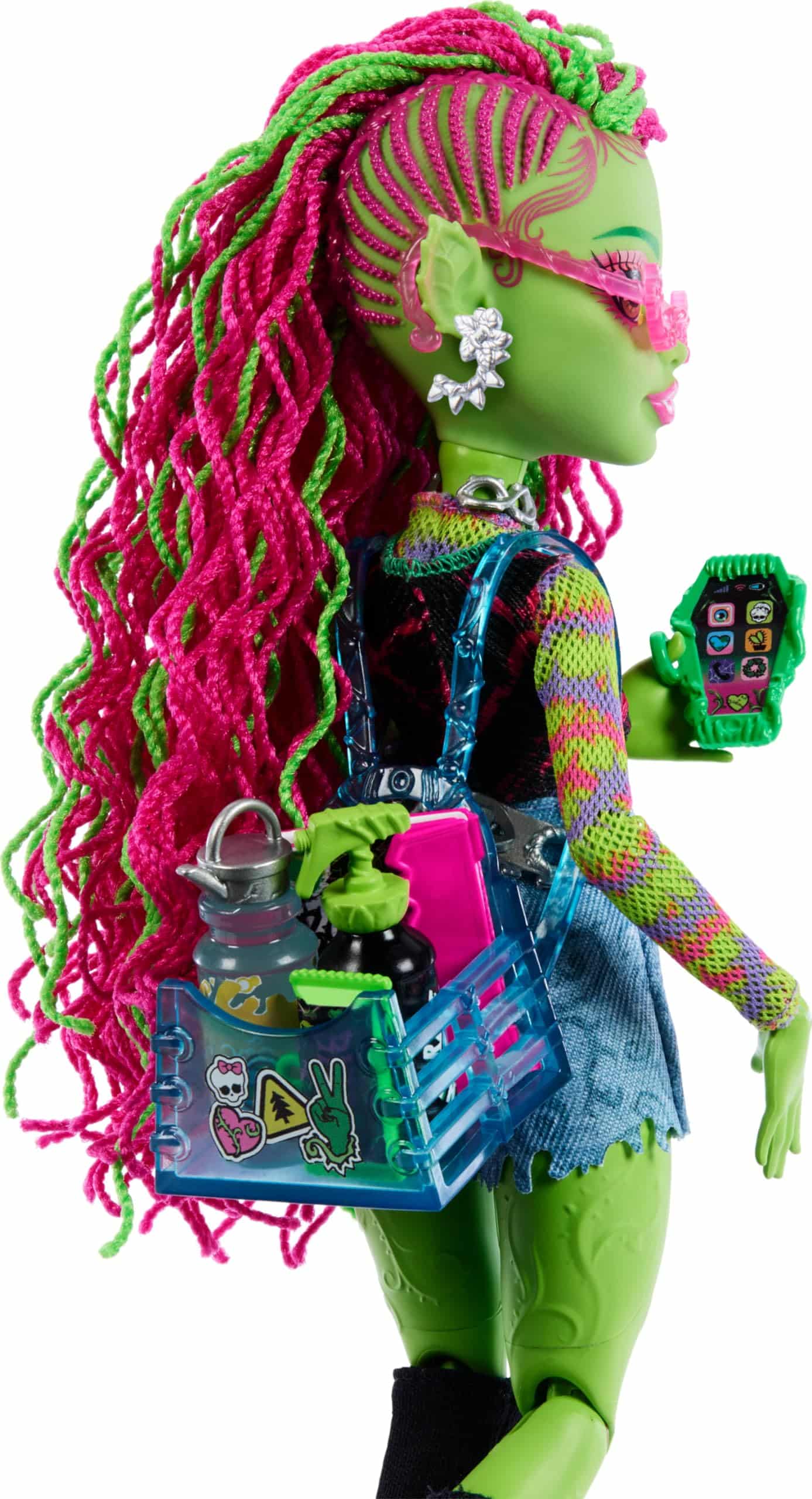 Trendy green-skin doll with pink braids, stylish outfit, and fun accessories in a clear backpack.